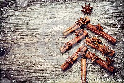Christmas card with Christmas fir tree made from spices cinnamon sticks, anise star and cane sugar on rustic wooden background Stock Photo