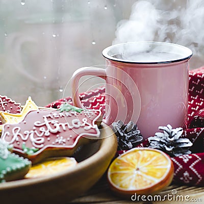 A cup of hot tea stands on a wooden table next to a wooden plate on which are gingerbread cookies made from orange slices against Stock Photo