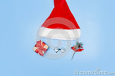 A Christmas card made of a Santa Claus hat, Santa glasses, a New Year's gift, branches of a fir tree on a blue background Stock Photo