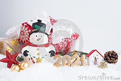 christmas card with snowman, gift box and number 2021 on the snow. Stock Photo