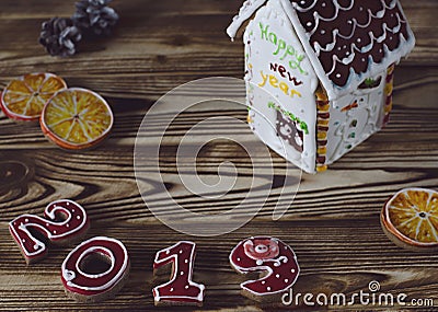 Christmas card on wood background gingerbread red numbers 2019 with slices of orange and white gingerbread house with a brown roof Stock Photo