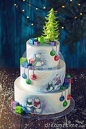 Christmas colorful three-Tiered cake decorated with drawings of Teddy bears, gift boxes and a green tree top Stock Photo