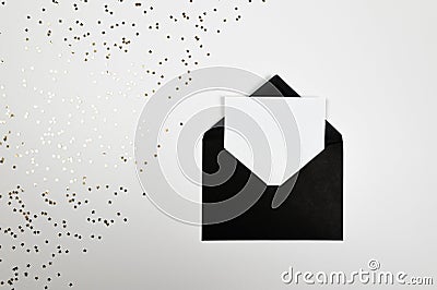 Christmas composition, black envelope, gold stars confetti on white background. Stock Photo