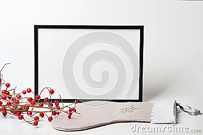 Christmas composition. Black frame and christmas sock with branches with red berries on white background. Stock Photo