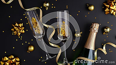 Christmas composition. Black Xmas background with champagne bottle, glasses, golden balls and decorations, confetti. Flat lay, top Stock Photo