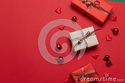 Christmas composition of surprise boxes decorated with shiny ribbons, red Christmas balls, heart shapes on a red background Stock Photo