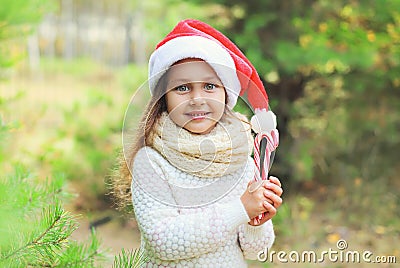 Christmas concept - portrait little girl child in santa red hat with sweet lollipop cane Stock Photo