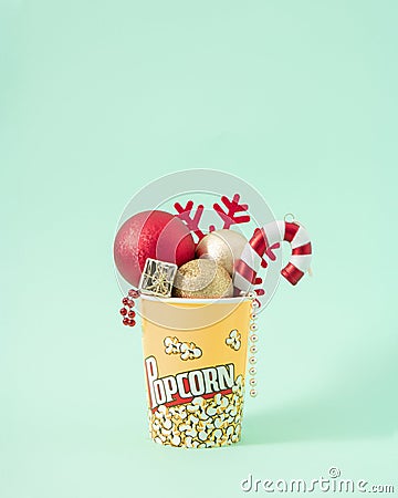 Christmas creative concept of New Year red decoration in popcorn box. Winter snack for the cinema on pastel mint background Stock Photo