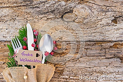 Christmas cutlery on rustic wood with label and german text, Frohe Weihnachten, means Merry Christmas Stock Photo