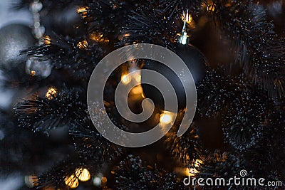 Christmas dark blurred background with a black Christmas tree, ornaments and bokeh lights Stock Photo