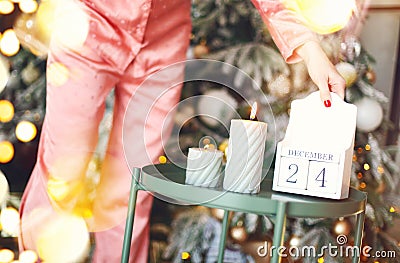 Christmas day. Woman in pajama flipping wooden calendar from 24 to 25 december in morning Stock Photo