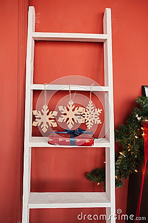 Christmas decor, white staircase, three snowflakes and a gift on the step against Stock Photo