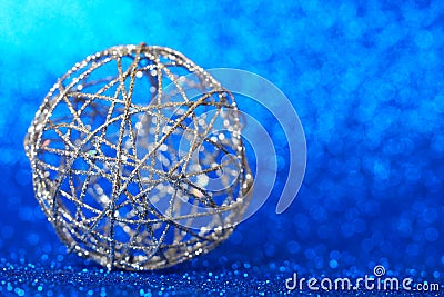 Christmas decoration - a ball of silver wire lies on a sparkling blue background. The long-awaited winter holiday. Blank for New Stock Photo