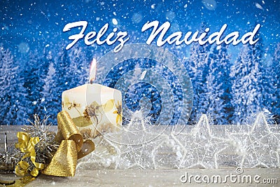 Christmas decoration with candle, golden bow, silver stars, with text in Spanish `Feliz Navidad` in a blue forest background Stock Photo