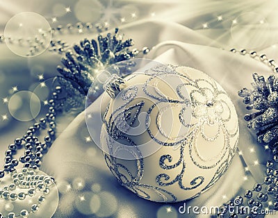 Christmas decoration. Christmas ball, pine cones, glittery jewels on white satin. Stock Photo