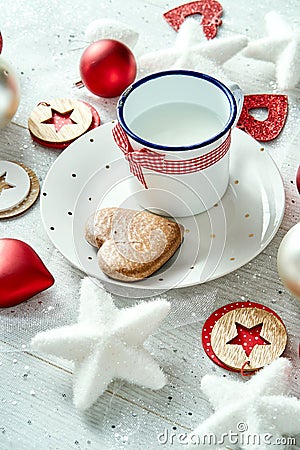 Christmas decoration with milk plate with gingerbread snowflakes and baubles on a white table. Stock Photo