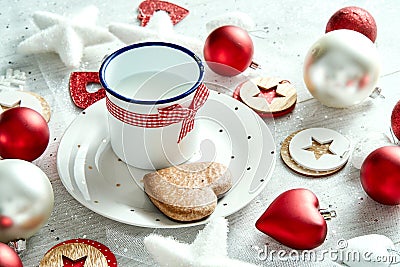 Christmas decoration with milk plate with gingerbread snowflakes and baubles on a white table. Stock Photo