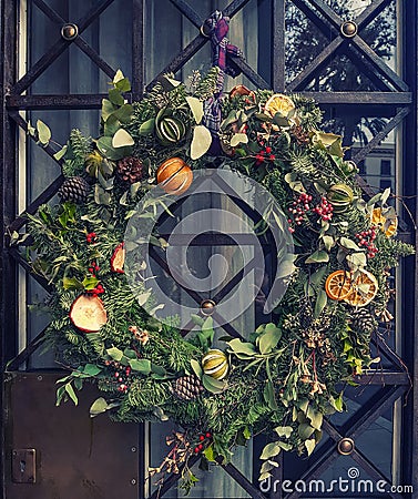 Christmas decoration outside the house door. Creative xmas wreath of pine branches, cones and citrus Stock Photo