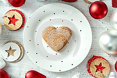 Christmas decoration with a white plate with gingerbread and baubles on a white table. Stock Photo