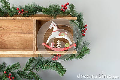 Christmas decoration from a wooden shelf, green branches of fir and pine, mistletoe, pine cone and wooden toy horse Stock Photo