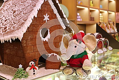 Christmas Decorations with Cute Elephant Soft Toy in Santa Costume and Marzipan Snowman in front of Gingerbread House Stock Photo