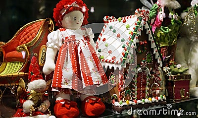 Christmas decorations in toy shop window including traditional red ragdoll and Gingerbread house Stock Photo