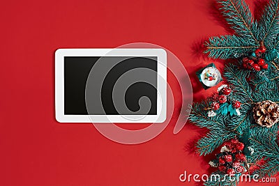 Christmas decorations and white tablet with black screen on hot red background. Christmas and New Year theme. Place for Stock Photo