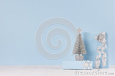 Christmas decorative silver tree with gifts and ribbons on white wood table and pastel blue wall. Stock Photo