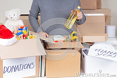 Christmas donations for charity. Man volunteer collecting food, clothes, kid toys, books into donation boxes. Donation Stock Photo