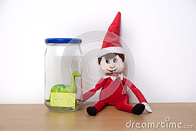 Christmas Elf mischief, elf puts toy dinosaur in a jar Stock Photo