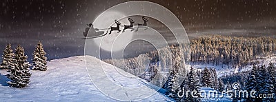 Christmas eve scene with tree, snow falling, Santa Claus in a sleigh with Reindeers flying in the sky Stock Photo