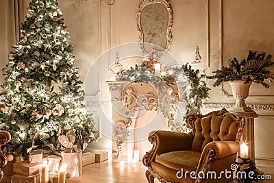 Christmas evening by candlelight. classic apartments with a white fireplace, decorated tree, sofa, large windows and Stock Photo