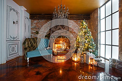 Christmas evening by candlelight. classic apartments with a white fireplace, decorated tree, sofa, large windows and Stock Photo