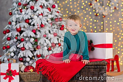 Christmas family child boy posing on wooden box close to presents and white fancy new year tree wearing red and green clothes Stock Photo