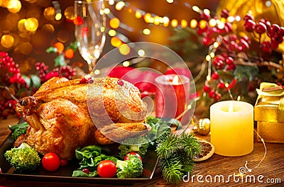 Christmas family dinner. Roasted chicken on holiday table, decorated with gift boxes, burning candles and garlands. Roasted turkey Stock Photo