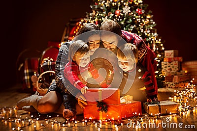 Christmas Family open Lighting Present Gift Box under Xmas Tree, Happy Mother Father Children Stock Photo