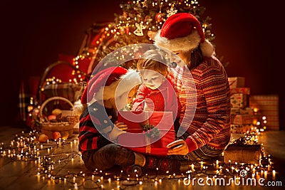 Christmas Family opening Lighting Present Gift Box under Xmas Tree, Happy Mother and Children Stock Photo