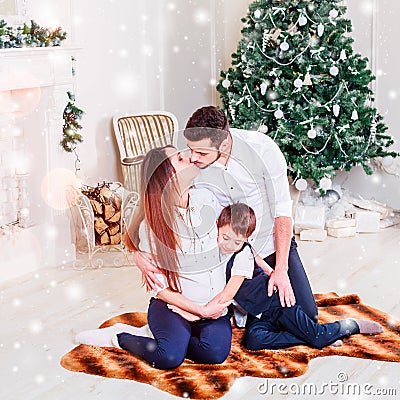 Christmas family smiling and kissing near the Xmas tree. Living room decorated by Christmas tree and present gift box Stock Photo