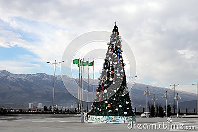 Christmas fir-tree on a square of Ashgabad and mountains as back Stock Photo