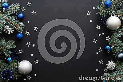 Christmas frame border with blue and sliver modern decorations, baubles, fir tree branches, confetti on dark black background. Stock Photo