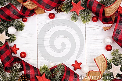 Christmas frame of ornaments, branches, burlap and red and black buffalo plaid ribbon, overhead view on a white wood background Stock Photo