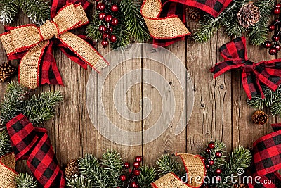 Christmas frame with red and black checked buffalo plaid ribbon, burlap and branches, top view on a wood background Stock Photo