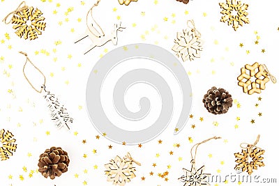 Christmas frame with wooden tree decoration, snowflakes, golden confetti and pine cones on white background. Flat lay, top view. N Stock Photo