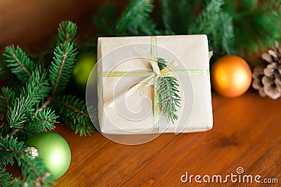 Christmas gift box with Christmas tree branch decor and gold ribbon on a wooden brown background. Stock Photo