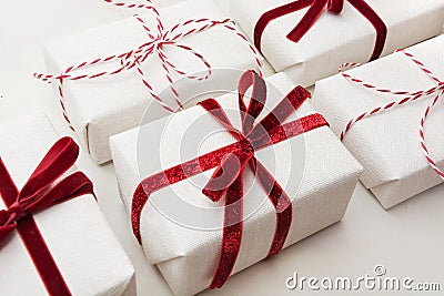 Christmas gift box wrapped in white paper and decorative red rope ribbon on marmoreal surface. Isometric. Close up. Stock Photo