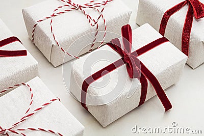 Christmas gift box wrapped in white paper and decorative red rope ribbon on marmoreal surface. Isometric. Close up. Stock Photo