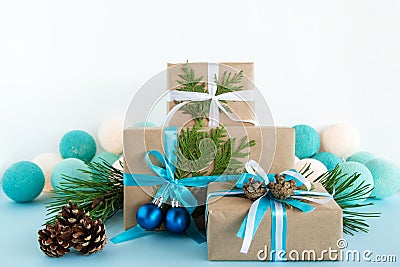 Christmas gift boxes wrapped of craft paper, blue and white ribbons and Christmas lights on the blue and white background. Stock Photo