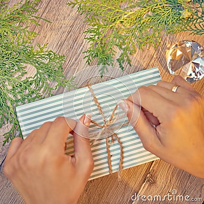 Christmas gift in hands, pine cones, thuja branches on wooden ba Stock Photo