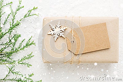 Christmas gift & tag with coniferous branch on snow white. Stock Photo