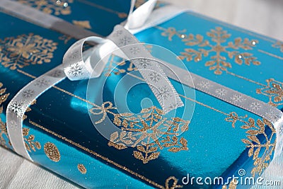 Christmas gift wrapped in blue with silver glitter snowflakes and bow Stock Photo